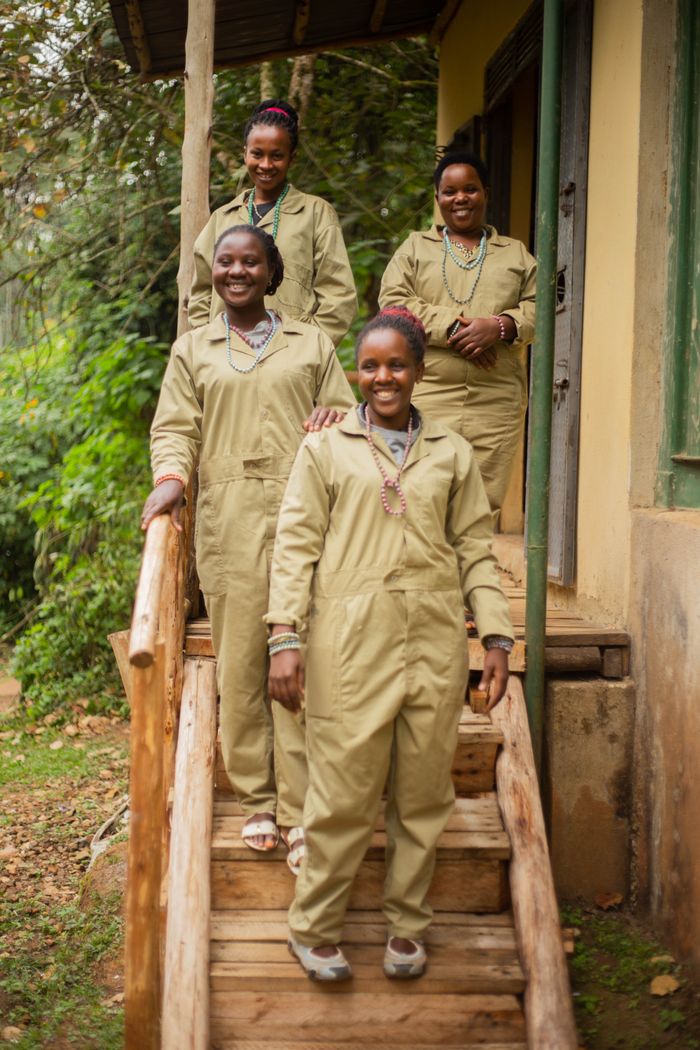 Four women in similar uniforms smiling on a wooden porch with greenery.