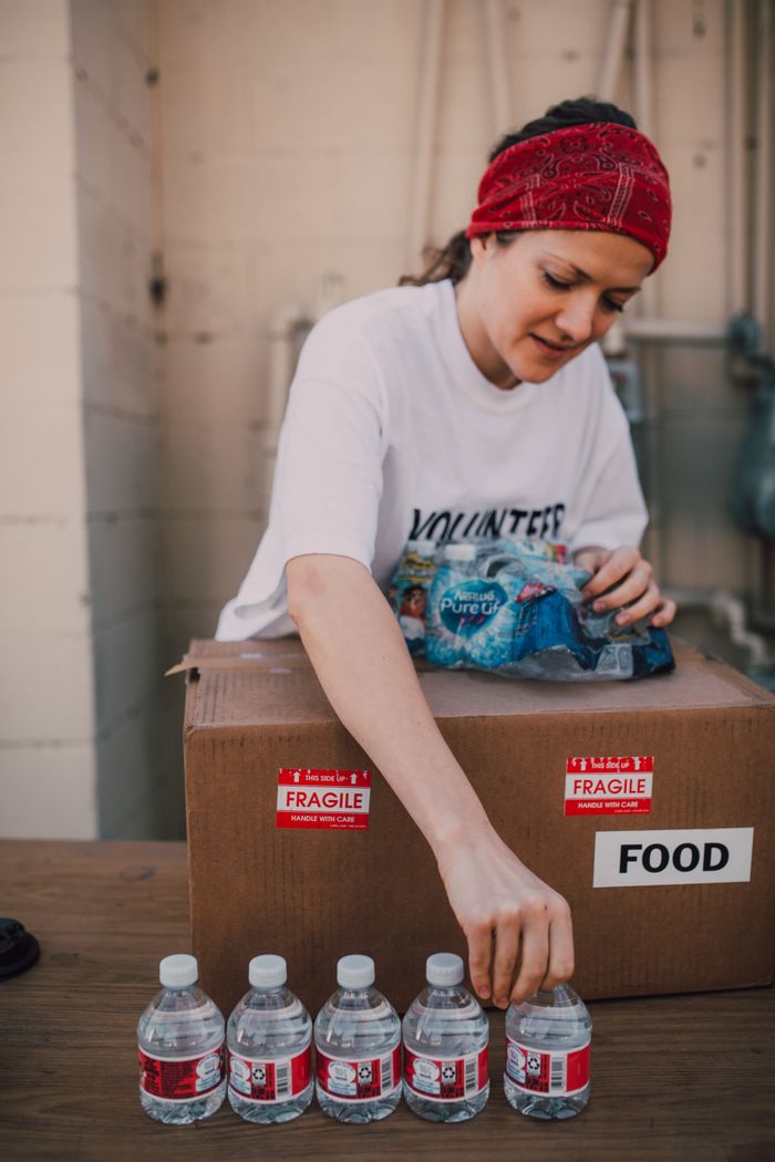 A woman volunteer organizes bottled water for a food distribution event.